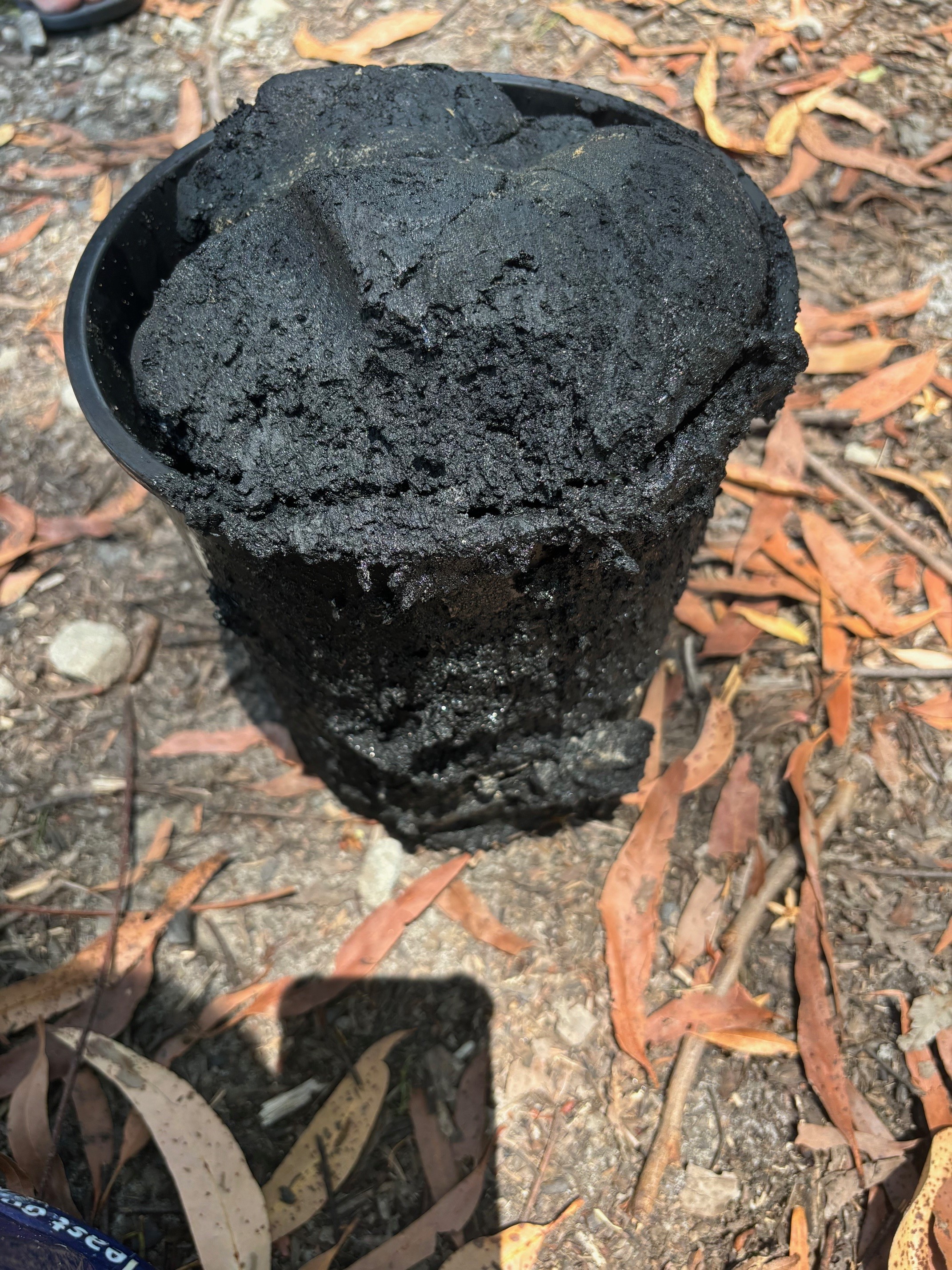 A big bucket overflowing with black greasy sludge