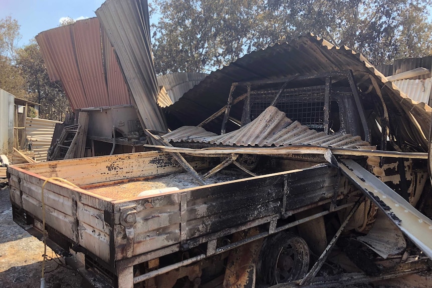 Sheets of warped and burnt corrugated iron on top of a singed ute.