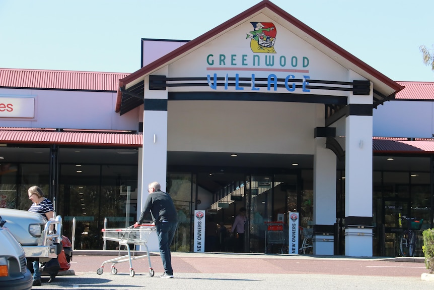 The front entrance to Greenwood Village Shopping Centre with shoppers in the car park.