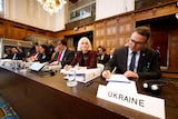 Courtroom panel, headed by a sign that says Ukraine 