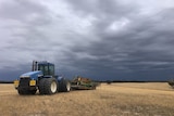 Tractor below brooding storm clouds