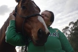 Horse nuzzles over woman's shoulder
