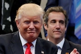 Donald Trump smiles with Michael Cohen in the background