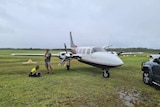 A man is questioned by police next to a plane.