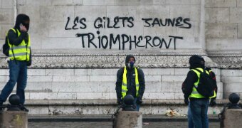 Demonstrators stand by graffiti at the base of the Arc de Triomphe.