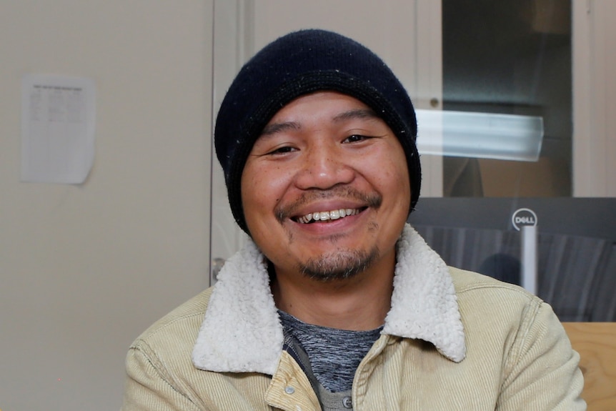 A man wearing a beanie and smiling.