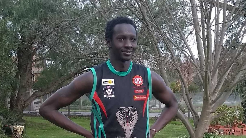 Lado Alphonse is dressed in his Cora Lynn Cobras team uniform as he stands in a garden.