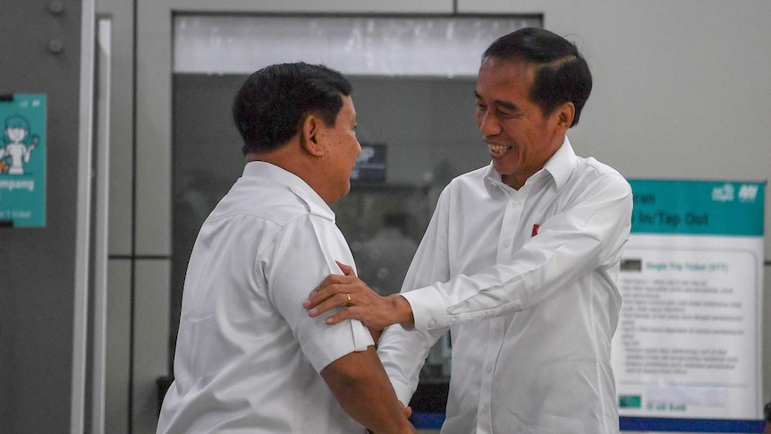 President Joko Widodo smiles and shakes hands with former election rival Prabowo Subianto