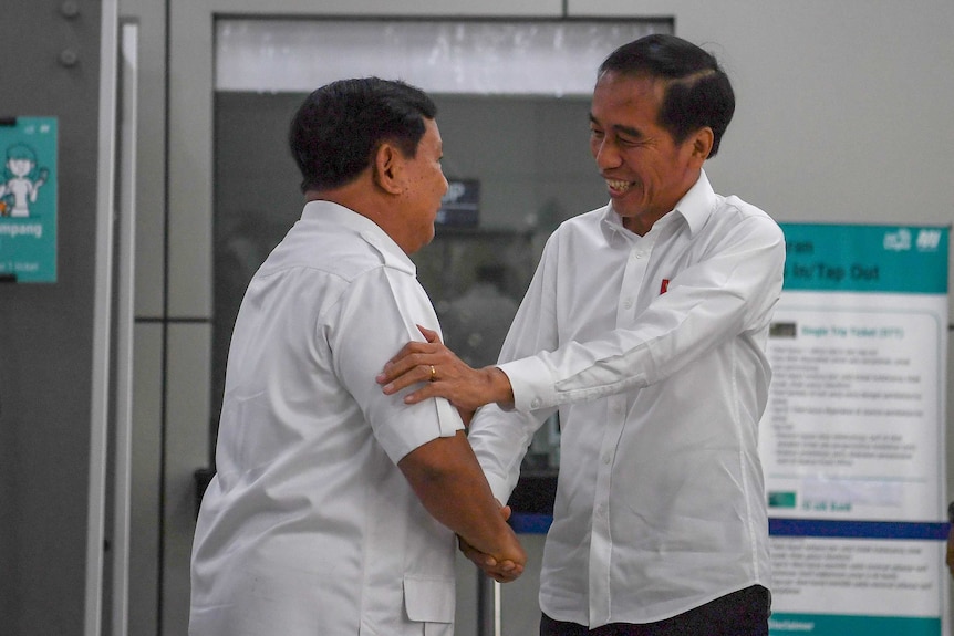 President Joko Widodo smiles and shakes hands with former election rival Prabowo Subianto