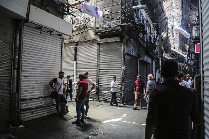 People lean up against closed shopfront roller doors