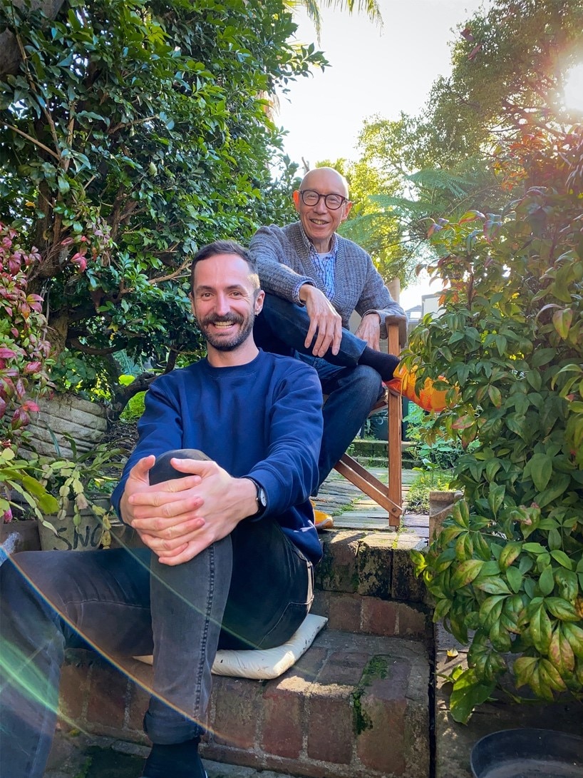 Two men sitting on steps in an outdoor garden.