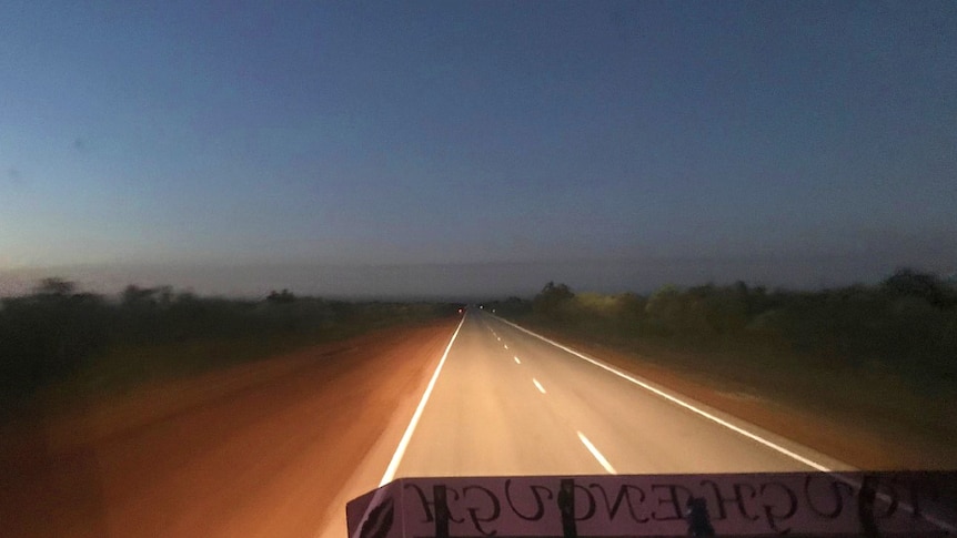The headlights of a road train light up the remote stretch of highway in the Pilbara.