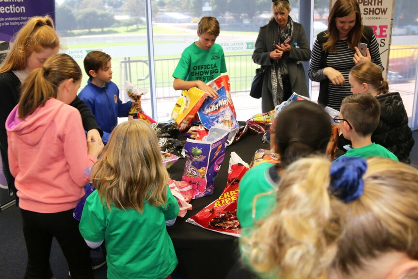 Children surround a table looking at show bags.