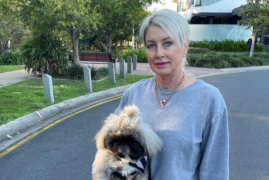 A woman with blonde hair holding a dog.