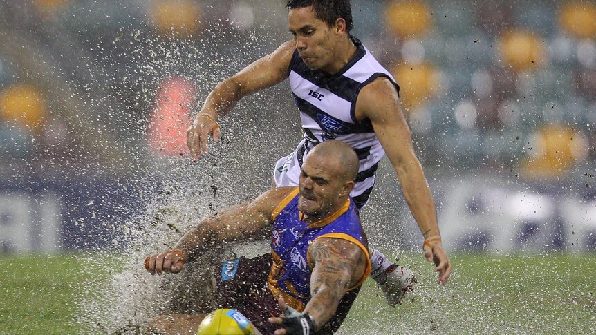 Ashley McGrath and Matthew Stokes battle for possession on the pond-like Gabba.
