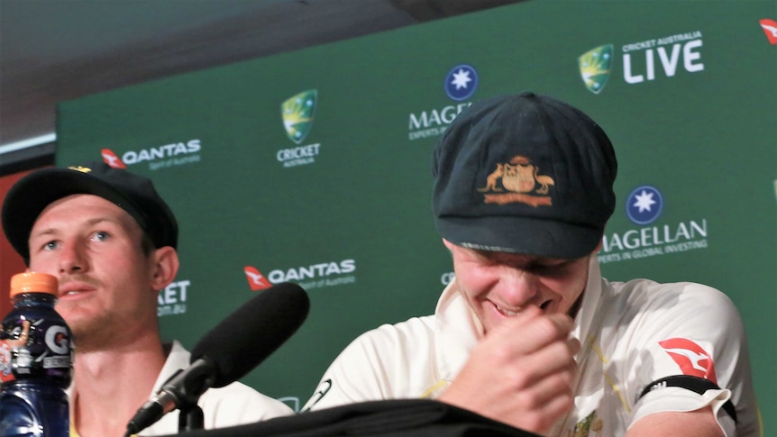 Steve Smith laughs while sitting next to Cameron Bancroft at a media conference.