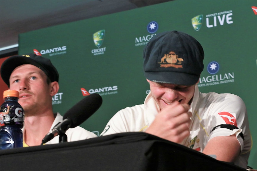 Steve Smith laughs while sitting next to Cameron Bancroft at a media conference.