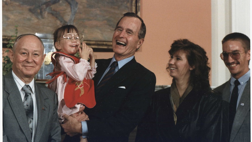 President George H W  Bush holds Jessica McClure