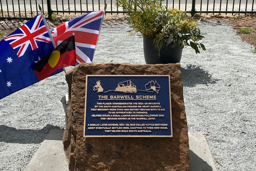 Plaque on a stone with the Australia, Aboriginal and United Kingdom flag in the background 