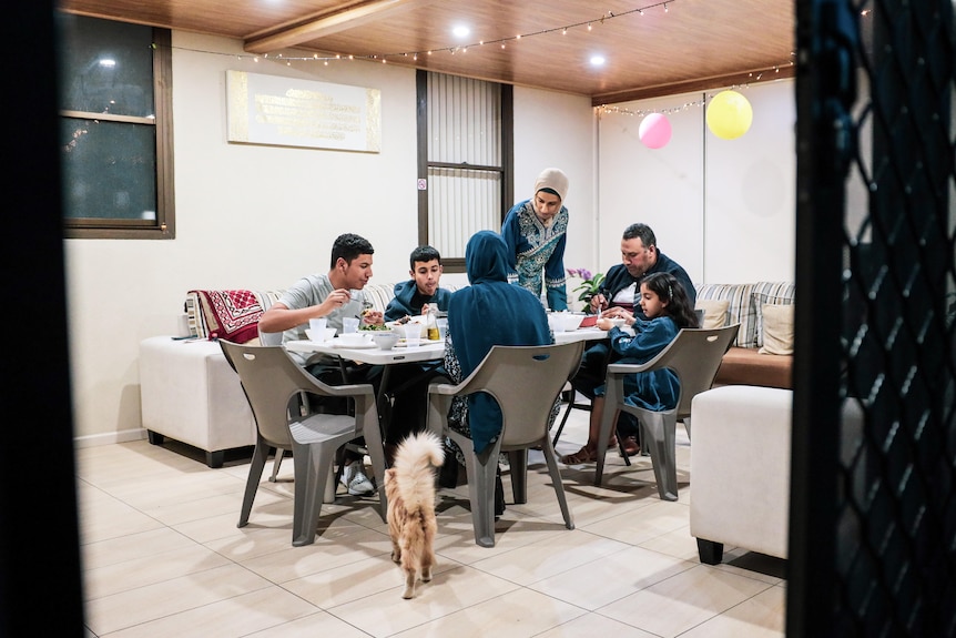 people sitting on chairs around a table eating