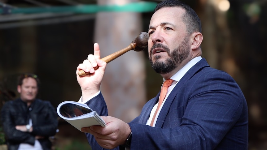 Sydney auctioneer Dion Moon holds the hammer before taking the winning bid.