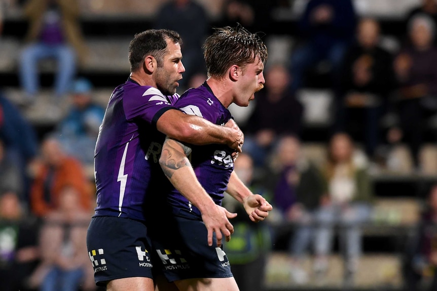 Two Melbourne Storm NRL players celebrate a try against the Gold Coast Titans.