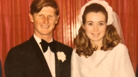 A man and woman stand smiling next to each other on their wedding day