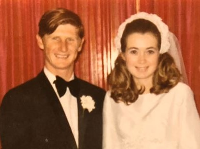 A man and woman stand smiling next to each other on their wedding day