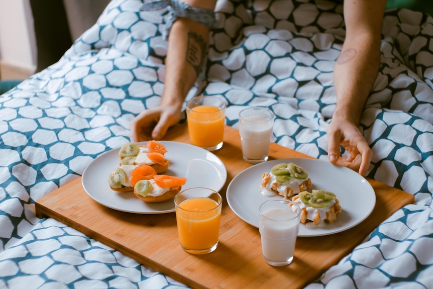 Breakfast in bed for two, served on a wooden board.