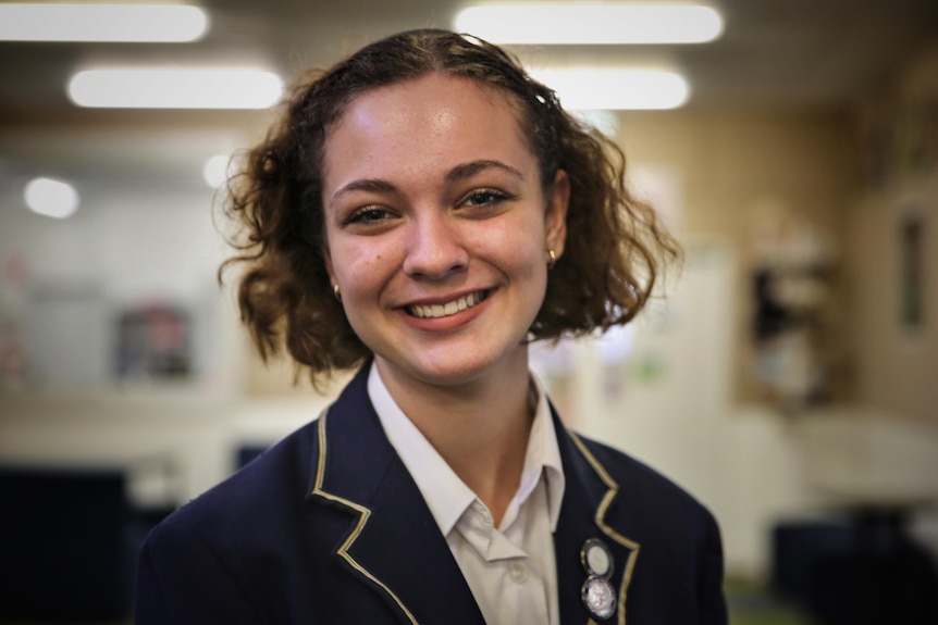 A portrait of Yasmin Toy, wearing a formal school jacket and smiling.