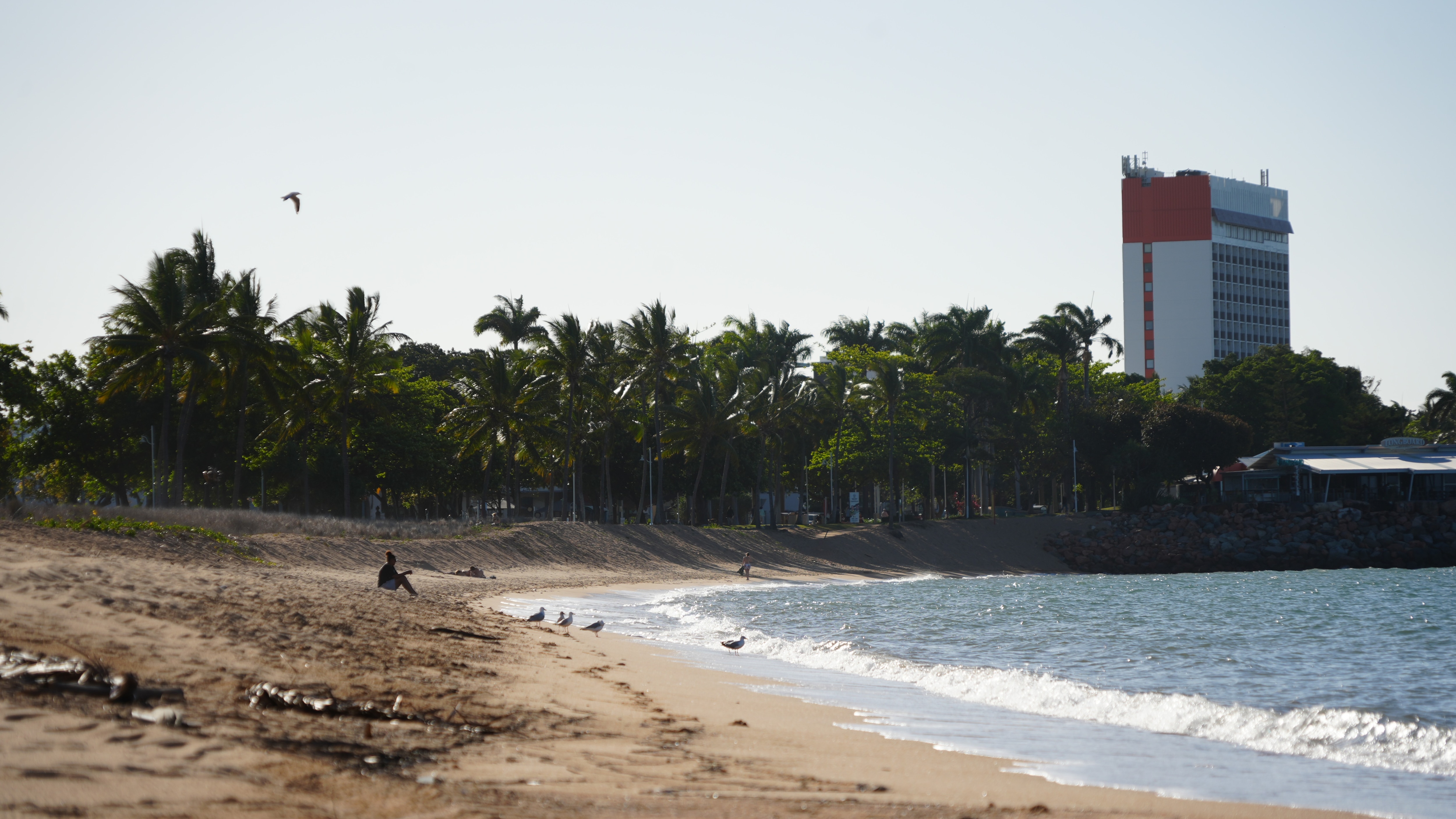 A person sitting on a sandy city beach.