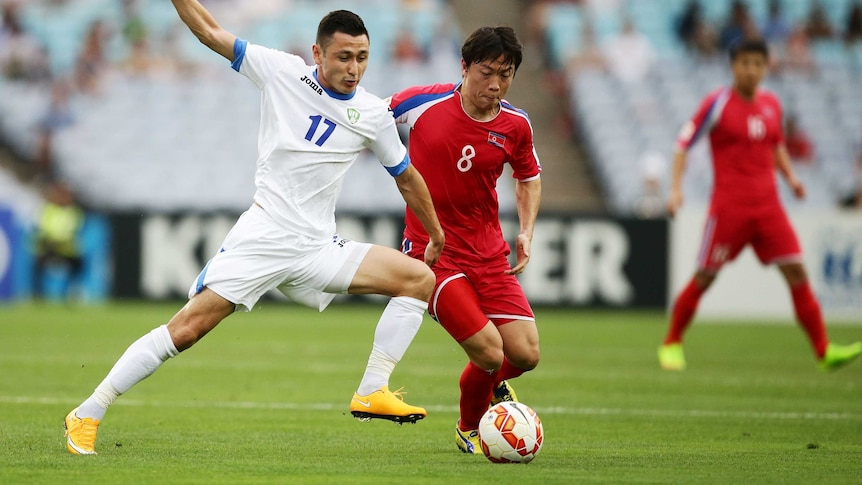 Uzbekistan's Sanjar Tursonov challenges North Korea's Ryang Yong Gi for the ball at the Asian Cup.
