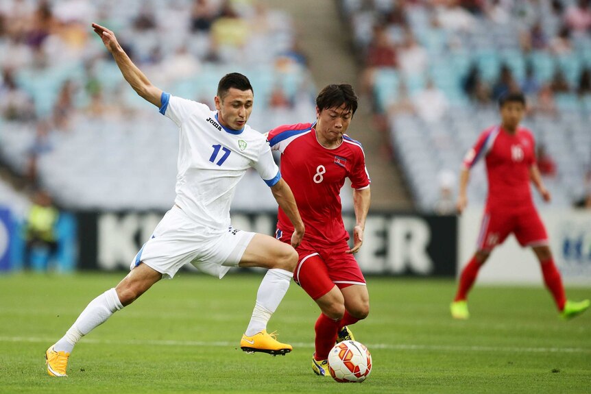 Uzbekistan's Sanjar Tursonov challenges North Korea's Ryang Yong Gi for the ball at the Asian Cup.