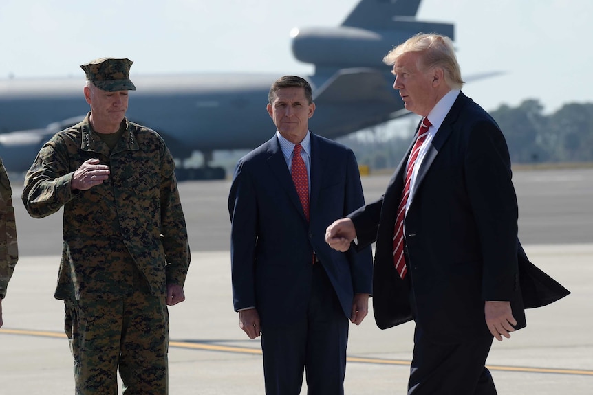 President Donald Trump passes Joint Chiefs Chairman General Joseph Dunford, left, and National Security Adviser Michael Flynn