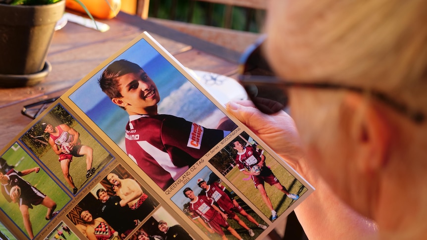 A woman with blond hair wearing sun glasses looks at a photo of a boy wearing maroon jersey