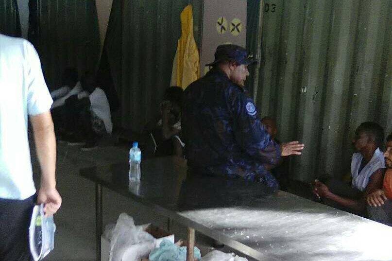 A man in uniform speaks to residents at the Manus detention centre.