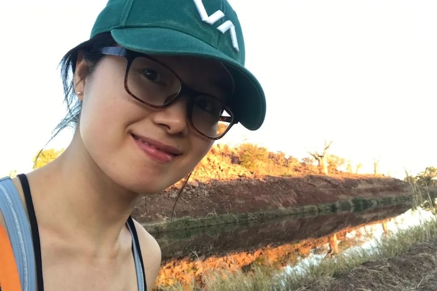 A selfie of Wenjing Wang wearing a green hat in the Australian outback.