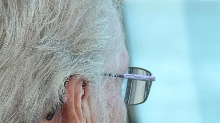 An elderly woman looks out a window