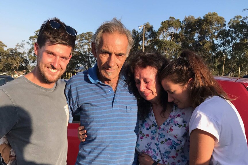 Mary and Dennis Gilbert are embraced by family after surviving the bushfire.