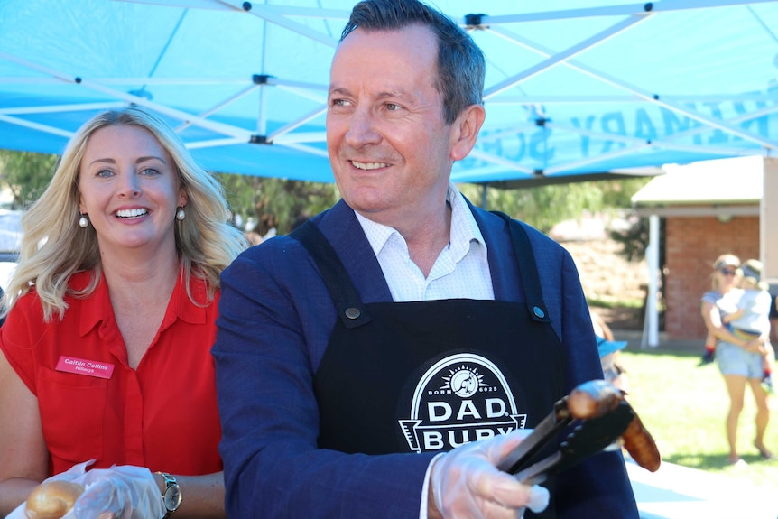 A picture of Mark McGowan holding a sausage in tongs above a barbeque next to Labor candidate Caitlin Collins.