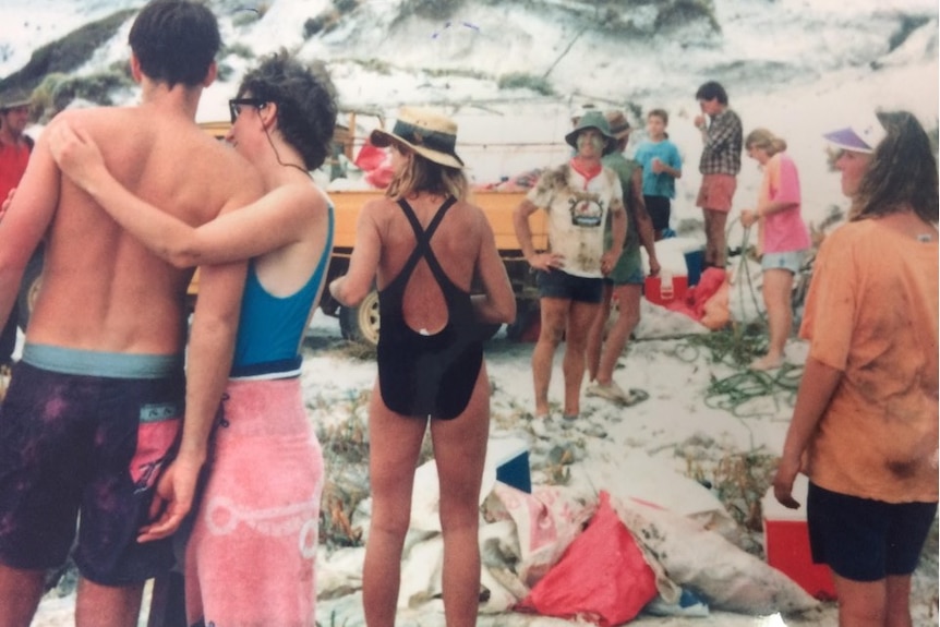 A crowd of people in swimwear working to clean up a beach.