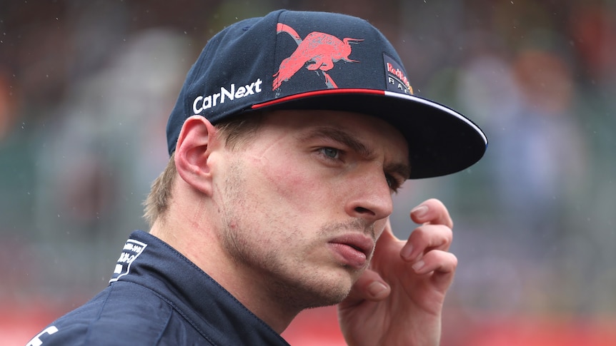Max Verstappen looks serious while wearing a Red Bull cap