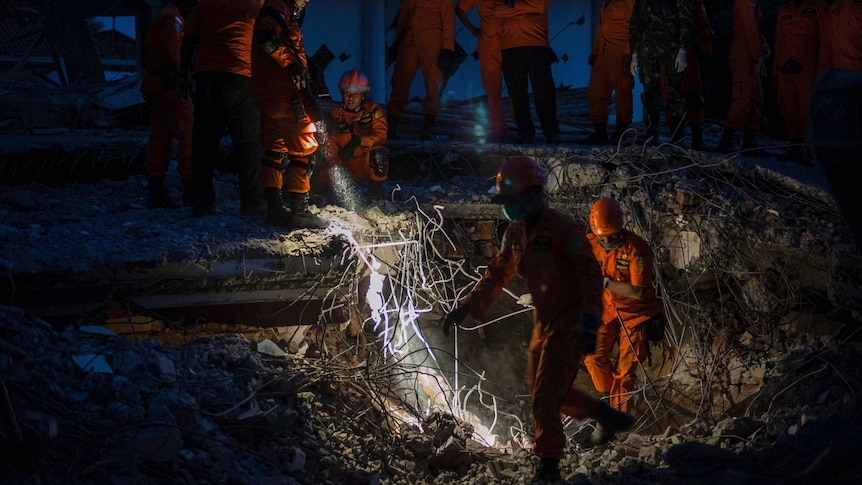 Rescuers search through rubble during the night time looking for earthquake victims.