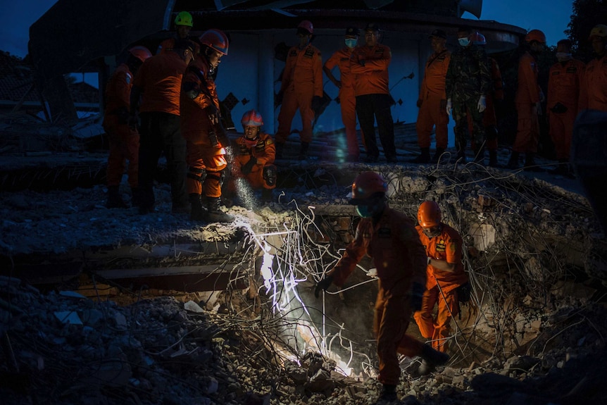 Rescuers search through rubble during the night time looking for earthquake victims.