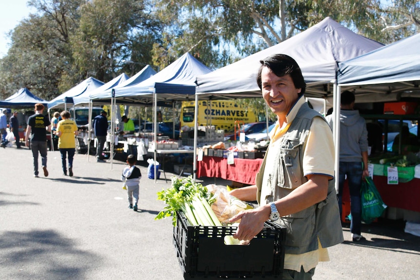 OzHarvest volunteer Abdul Malistani holds a crate of donated produce from the Southside Markets in Phillip.