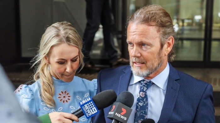 Craig McLachlan addresses the media outside a Sydney building with partner Vanessa Scammell beside him.