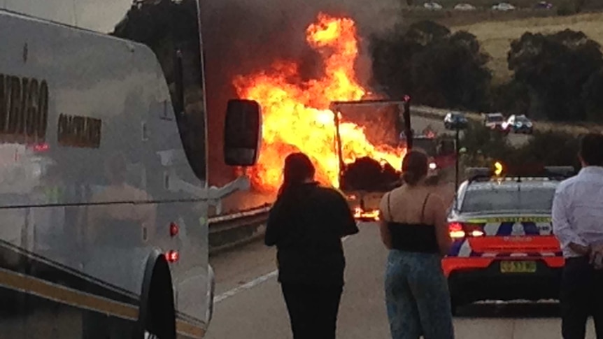 People watch as a truck burns.