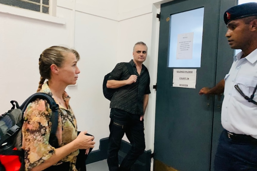 Yvette and John Nikolic stand in front of a door leading to a court room in Suva, Fiji.