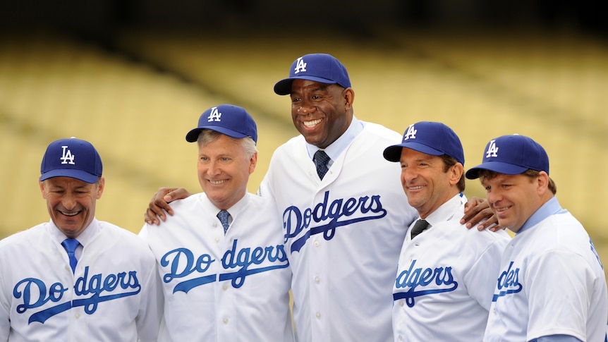 A group of men wearing white and blue uniforms smile for the cameras