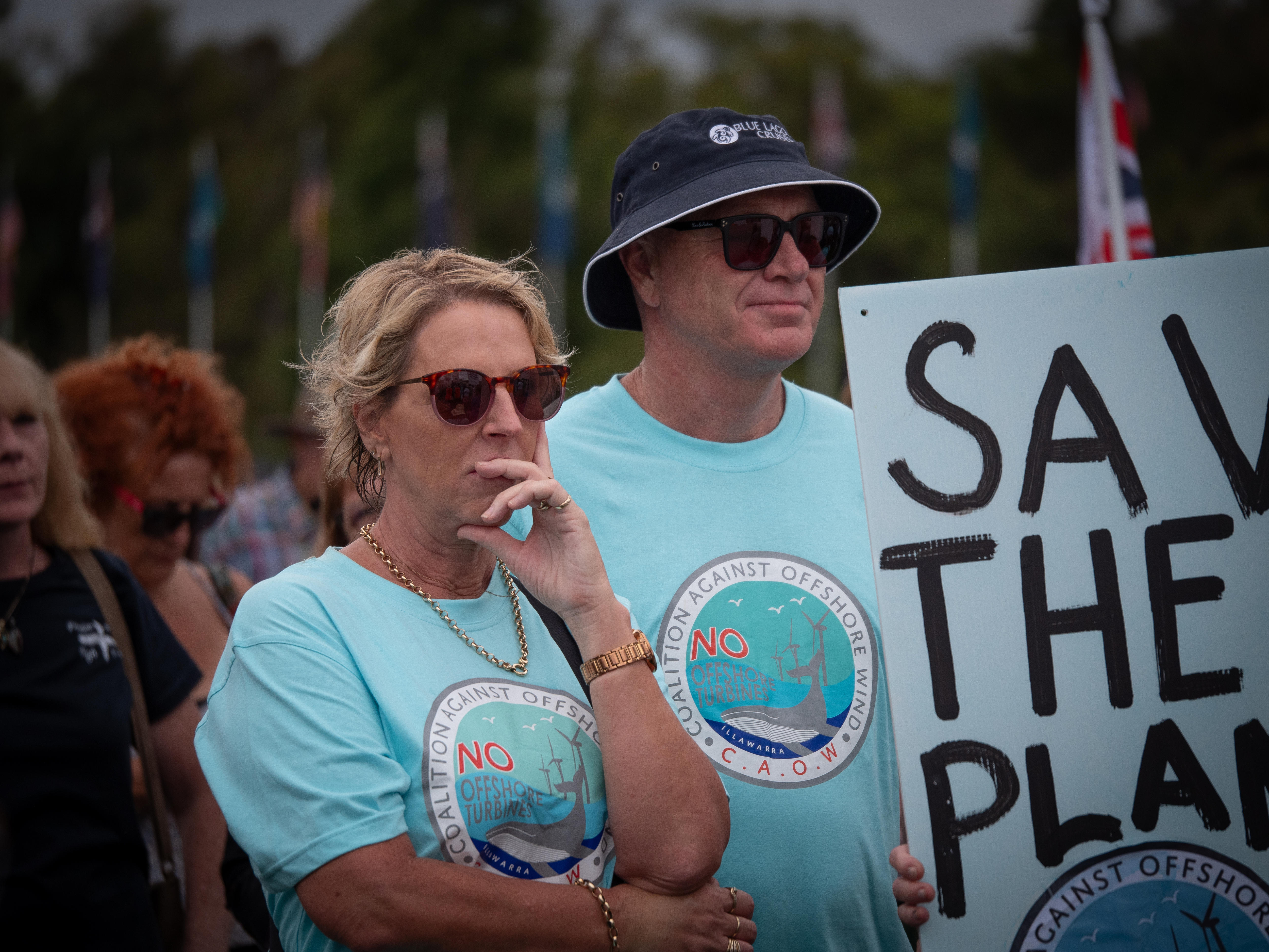 A couple is wearing 'Coalition against offshore wind' T-shirts at Reckless Renewables rally in Canberra.